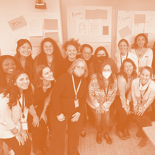 A group standing in front of a bulletin board, smiling