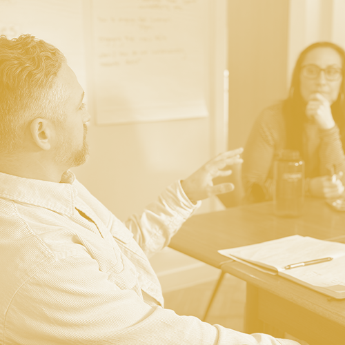 A leader and coach in conversation at a conference table